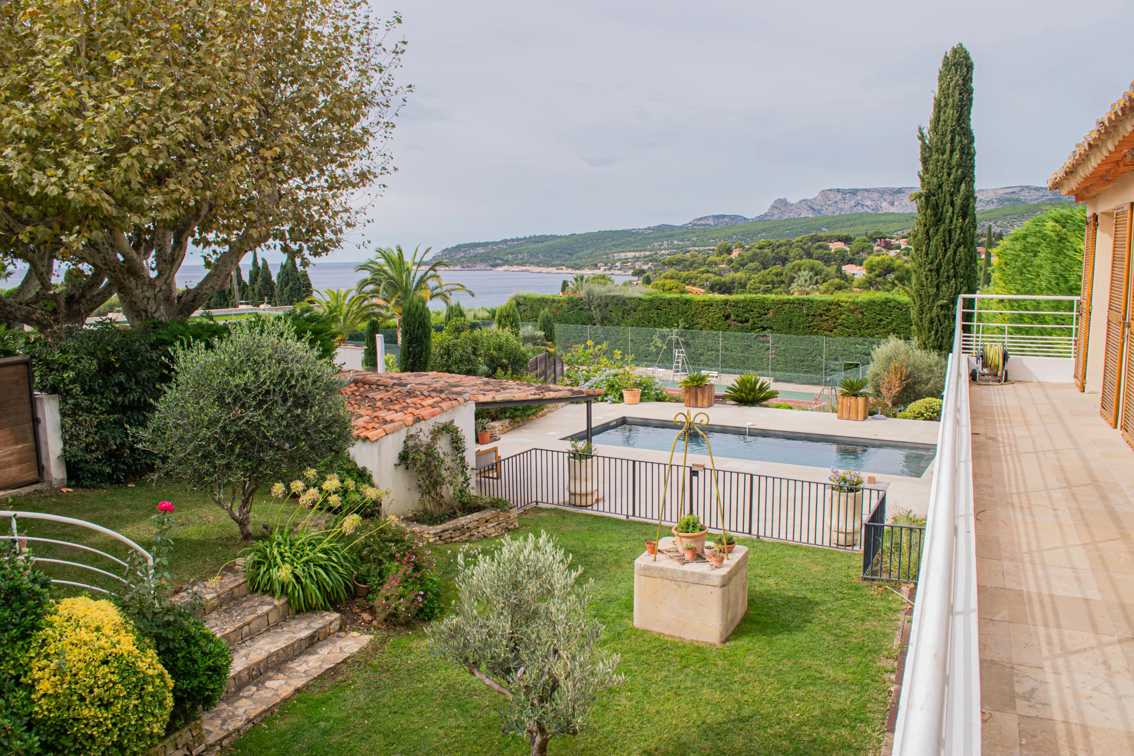 Jardin paysager avec vue sur une piscine et la mer à l'horizon.